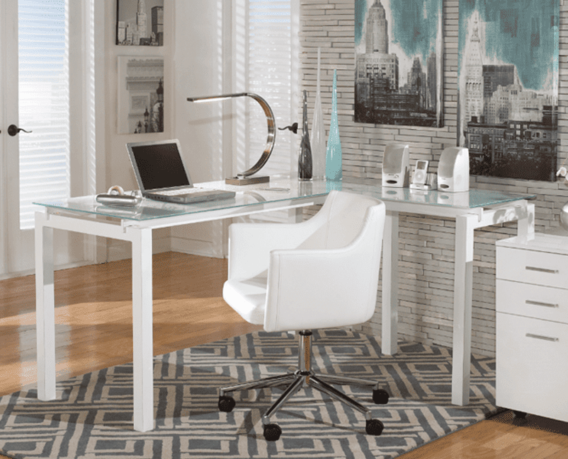 A contemporary home office setup with a glass-topped white desk, a white swivel chair, and a matching drawer unit, all on a blue and grey patterned rug, with a cityscape canvas adorning the wall behind.